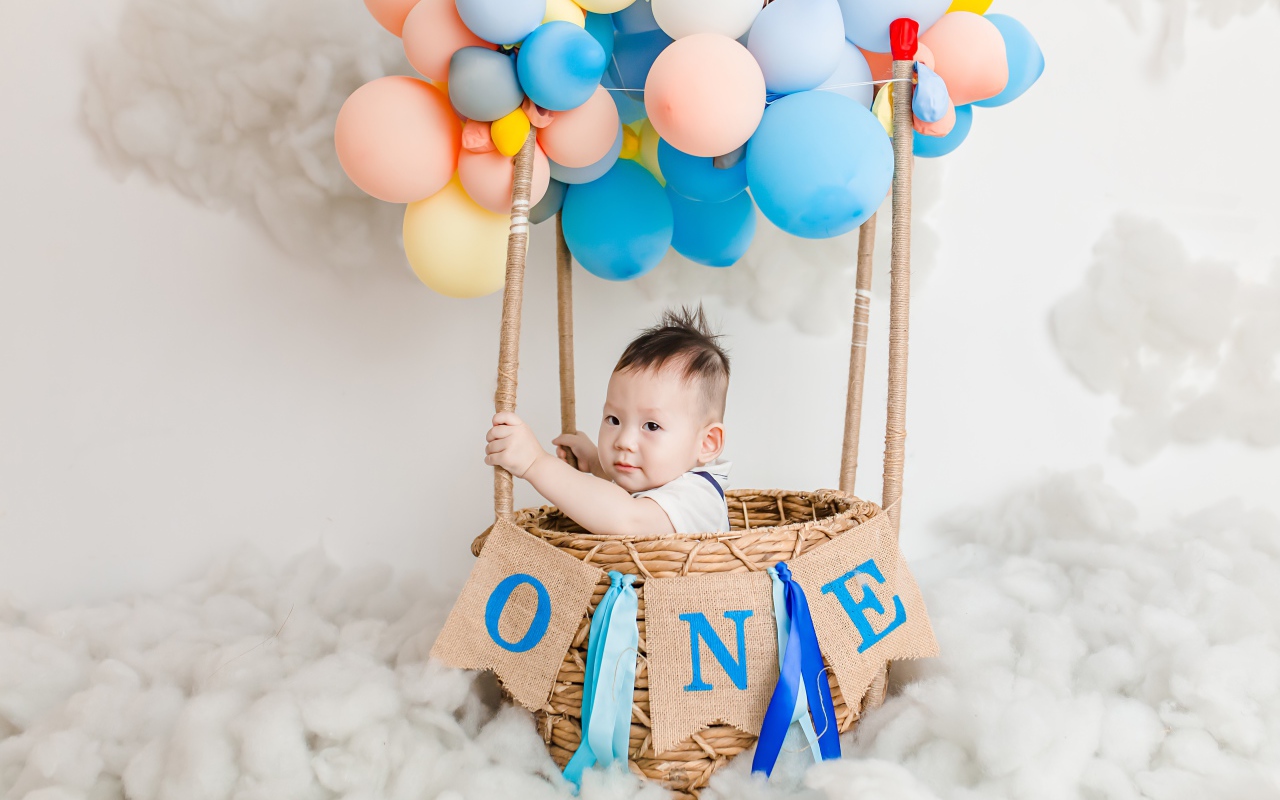 Маленький ребенок в корзине с шариками 