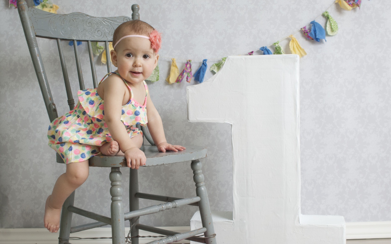 Маленькая девочка в платье на стуле