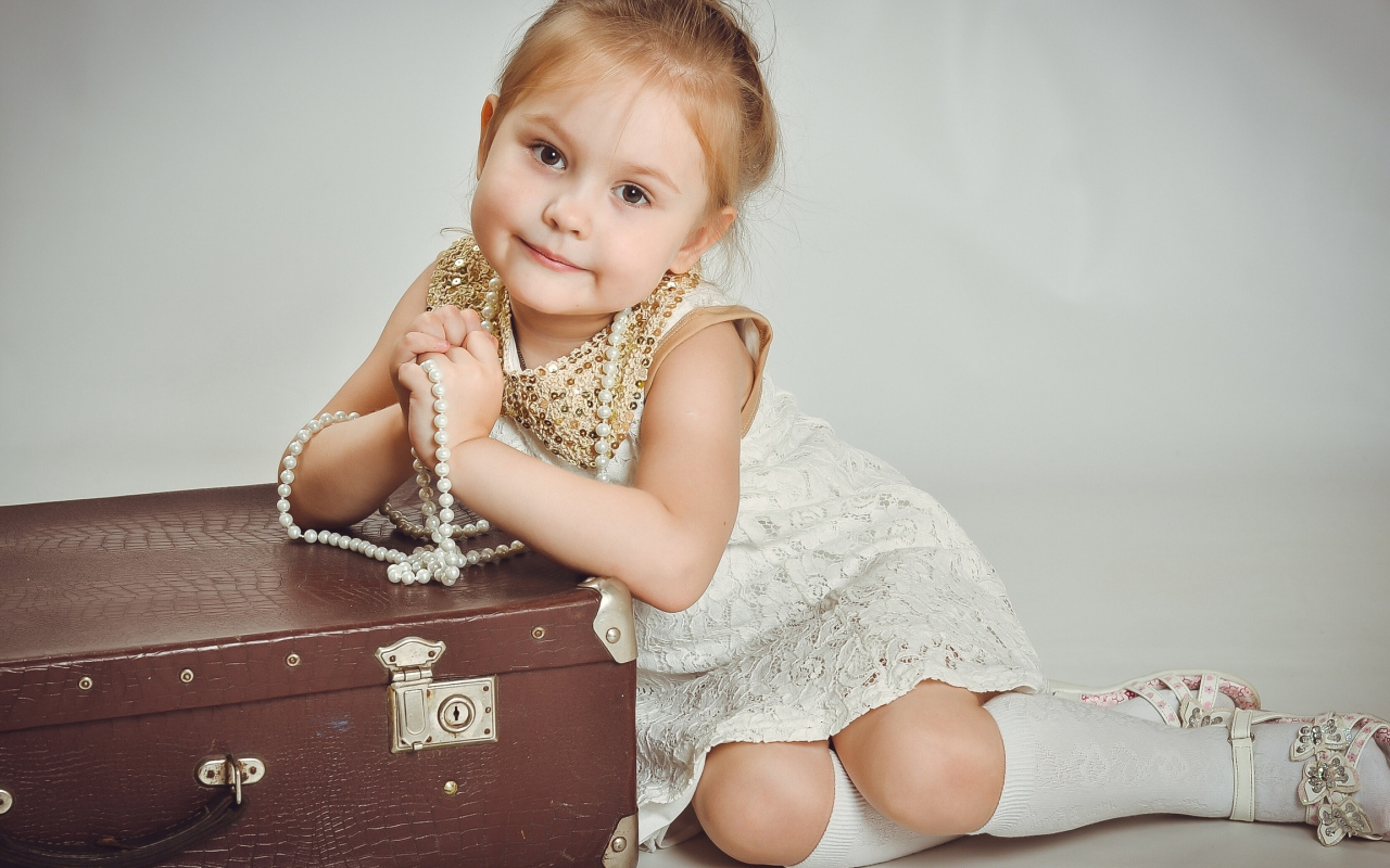Маленькая девочка в белом платье с чемоданом