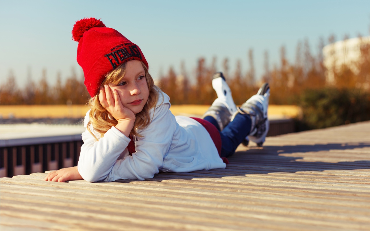 Маленькая девочка на роликах лежит на мосту