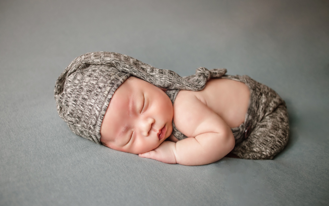 Маленький новорожденный ребенок на сером фоне