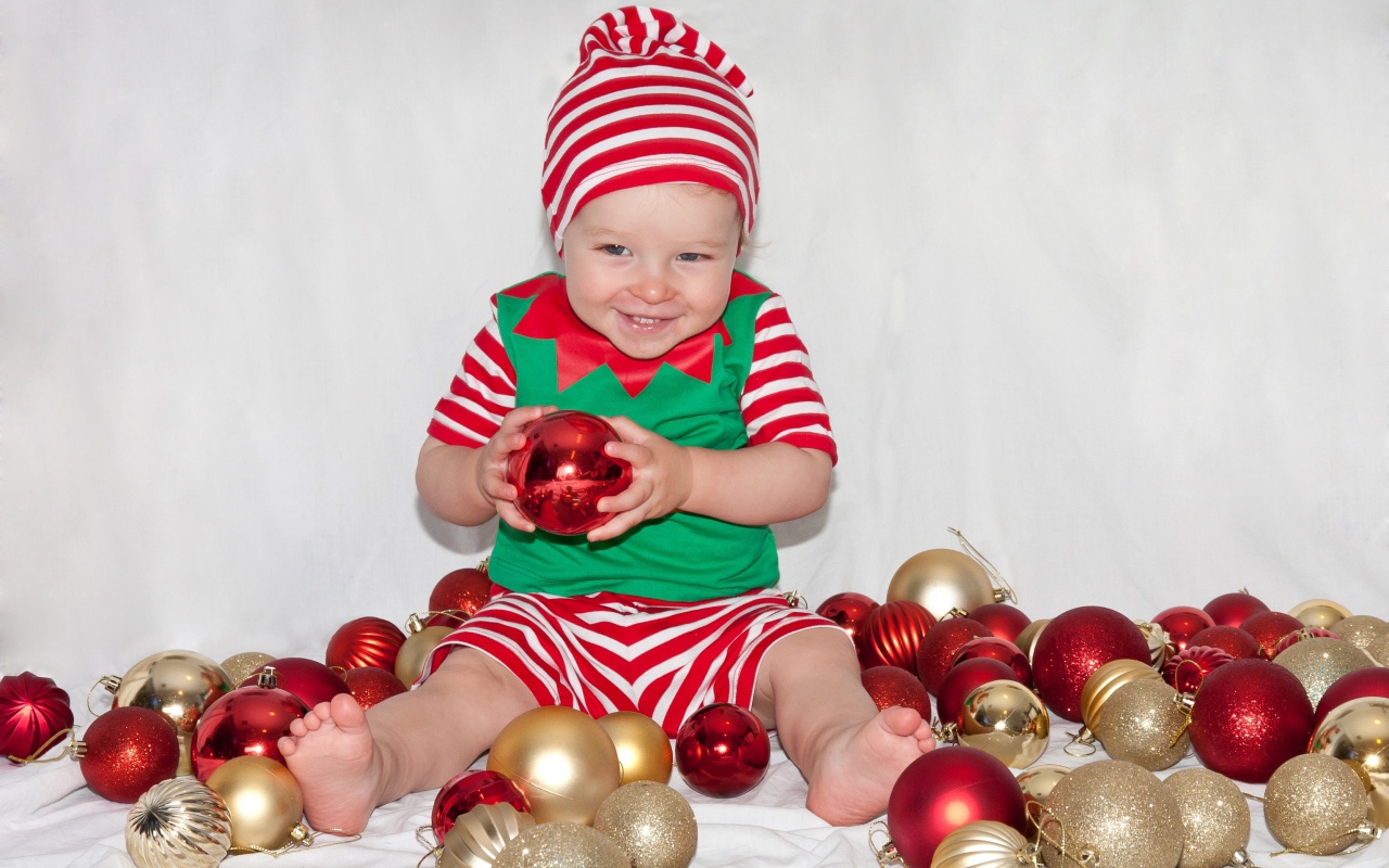 Маленький улыбающийся мальчик с елочными украшениями