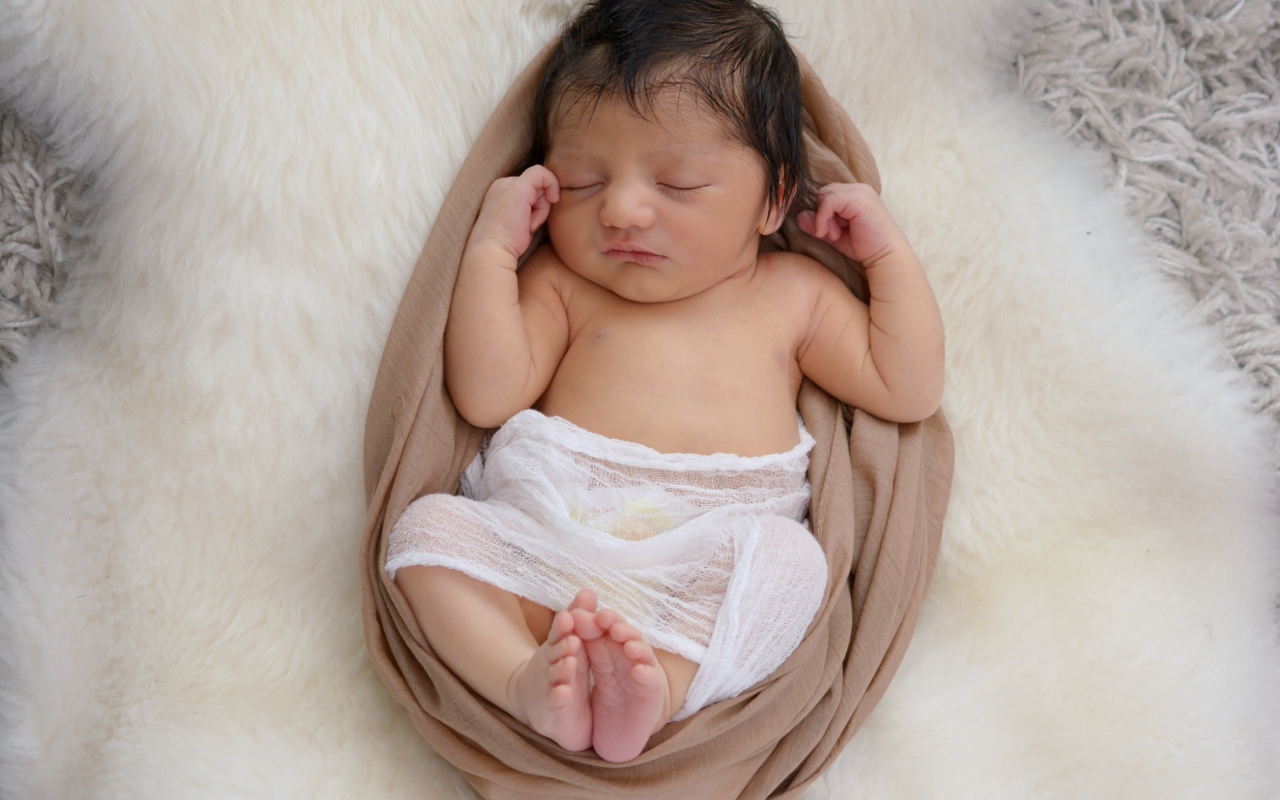 Спящий грудной ребенок на меховом покрывале 