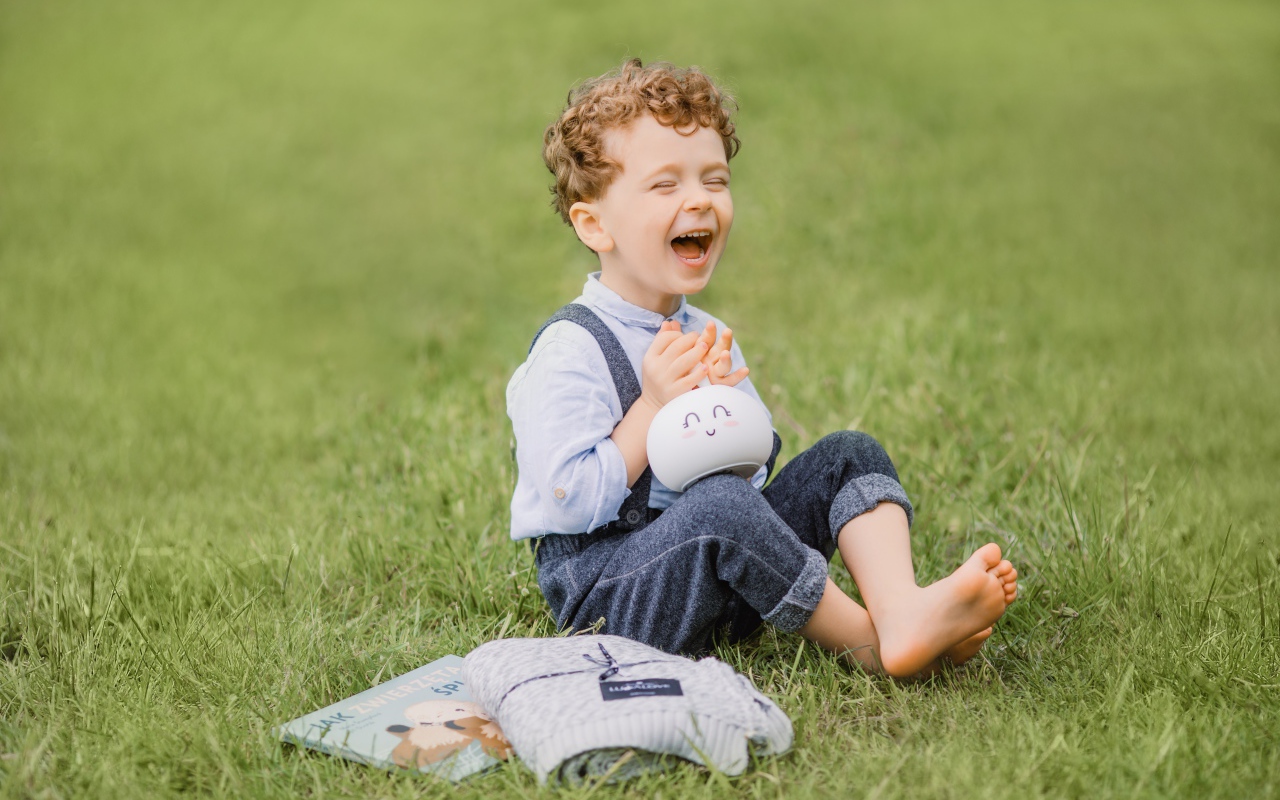 Улыбающийся мальчик сидит на траве