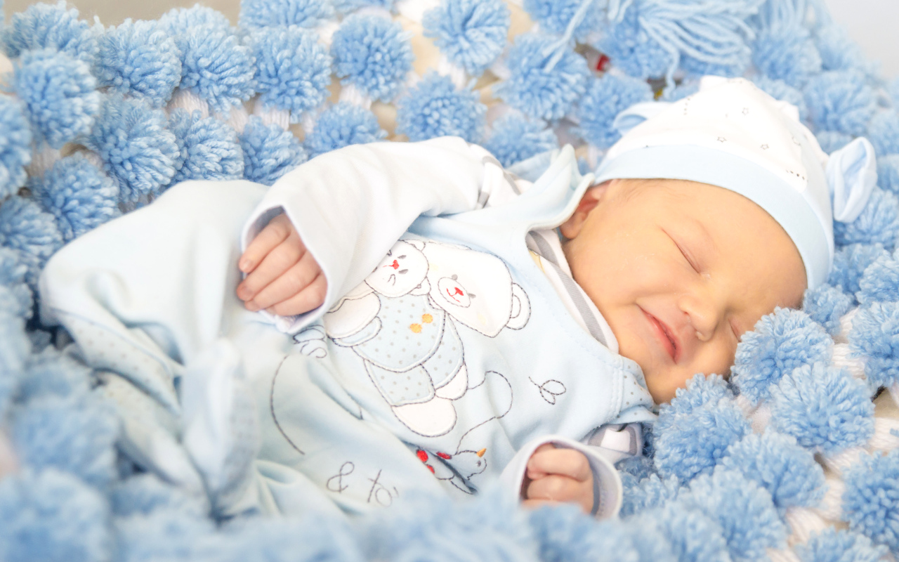 Улыбающийся грудной ребенок спит на голубом покрывале