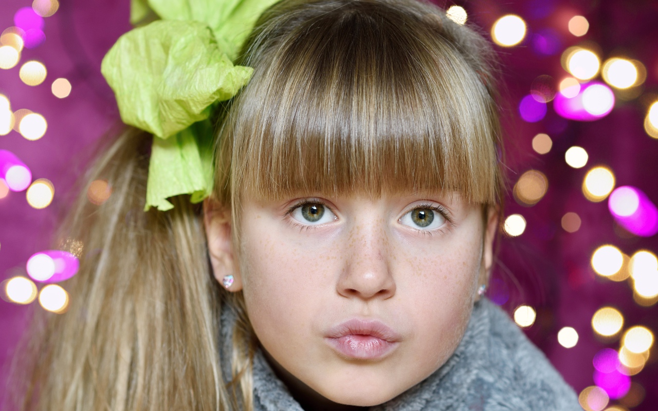 Лицо зеленоглазой девушки с бантом на голове 