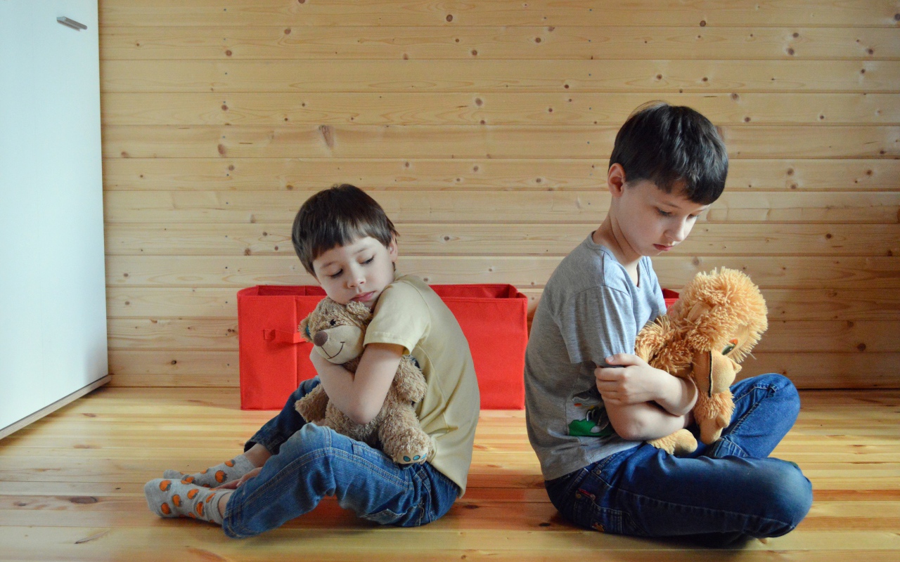 Два маленьких обиженных мальчика сидит на земле