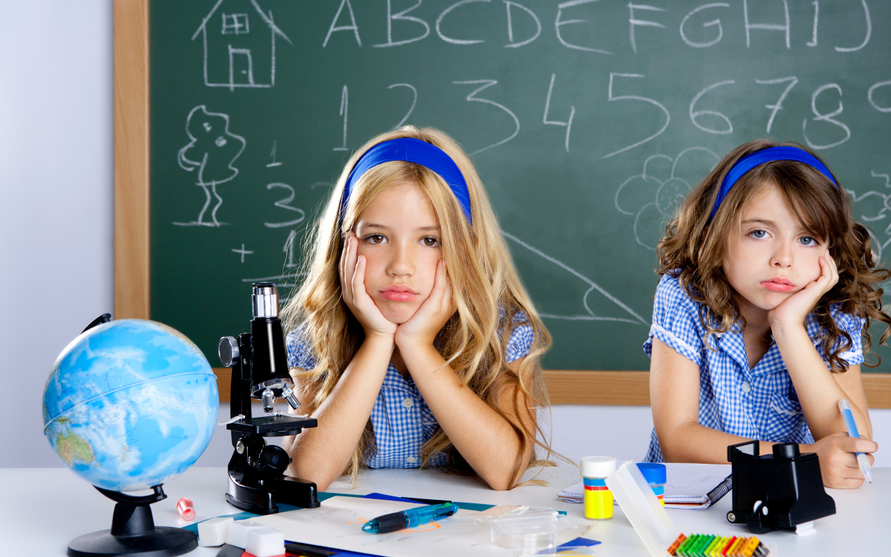 Две грустные девочка за партой в школе