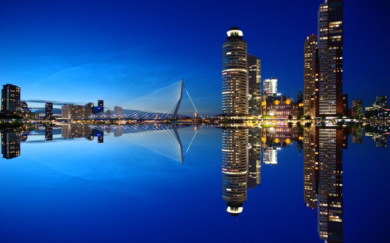 Небоскребы и мост отражаются в тихой воде