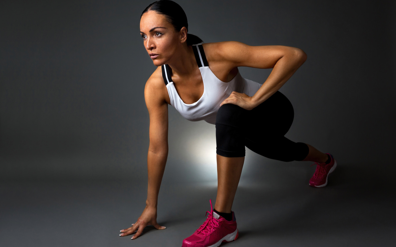 Девушка спортсменка в стойке на сером фоне 