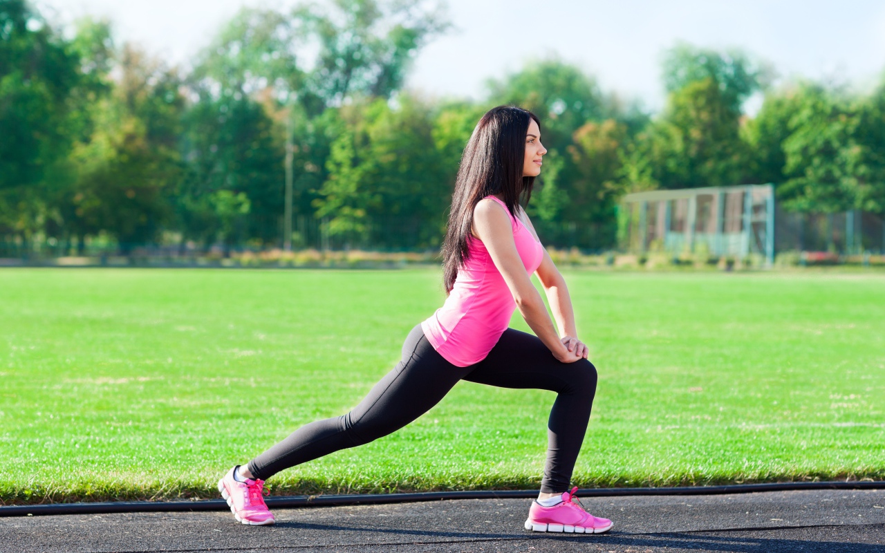 Девушка делает растяжку на поле 