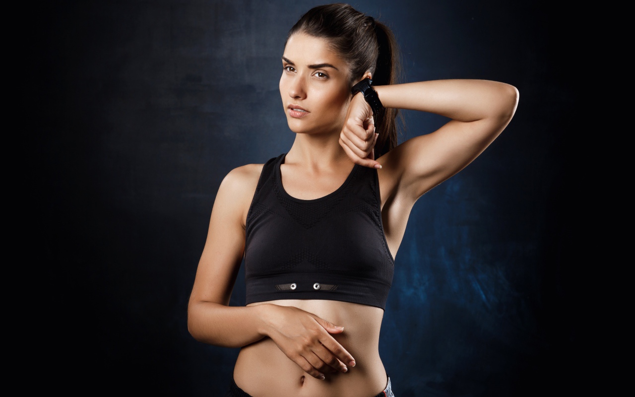 Спортивная девушка в черном топике с часами на руке 