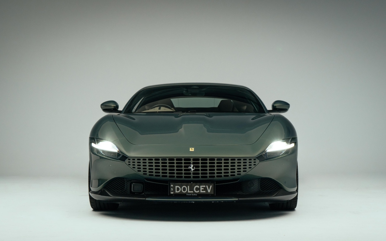 Автомобиль Ferrari Roma на сером фоне вид спереди