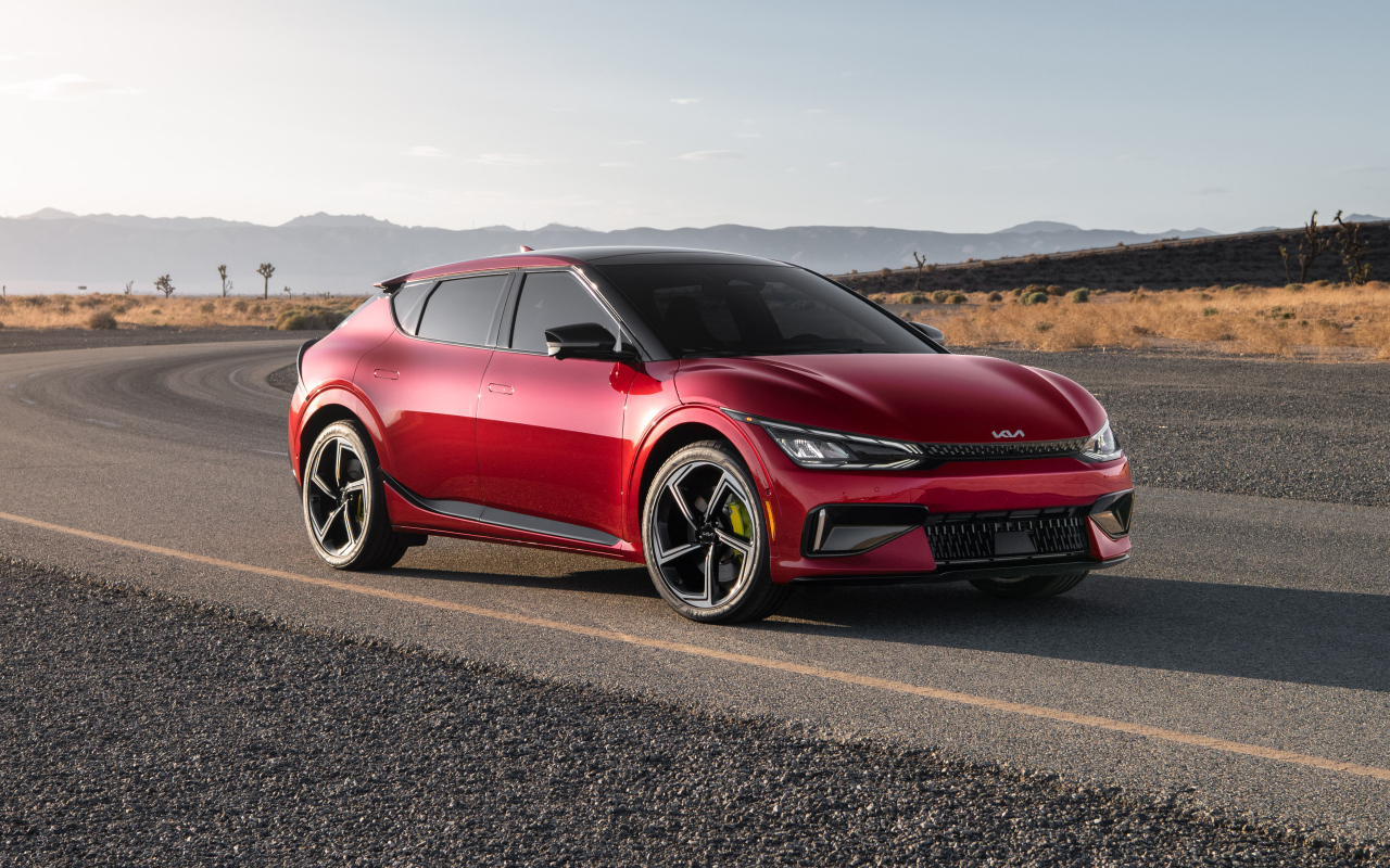 Красный автомобиль Kia EV6 GT 2023  года на дороге
