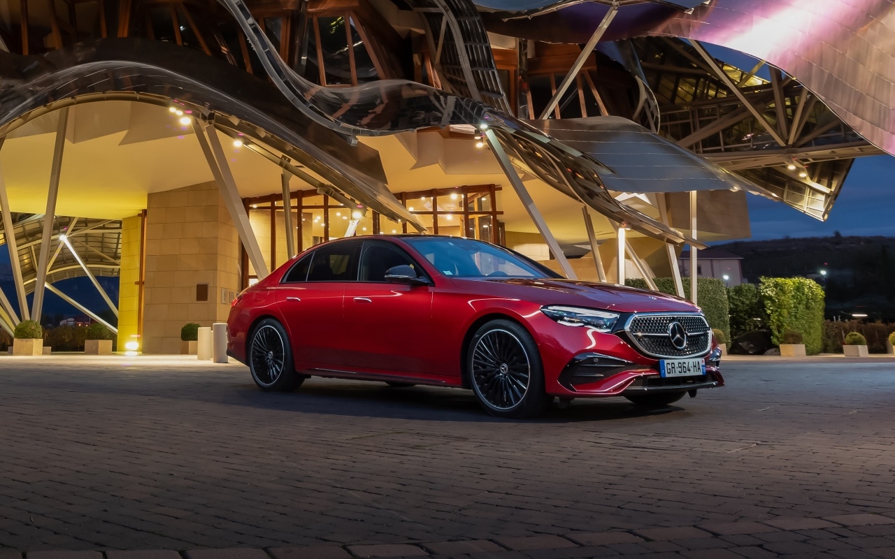 Красный автомобиль Mercedes-Benz E 220 D AMG Line у здания