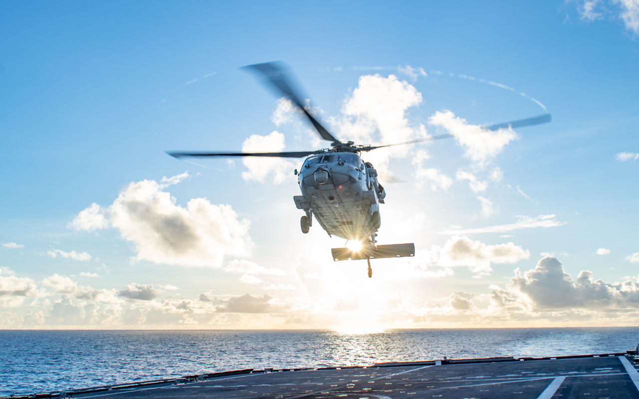 Военный вертолет приземляется на корабль в море
