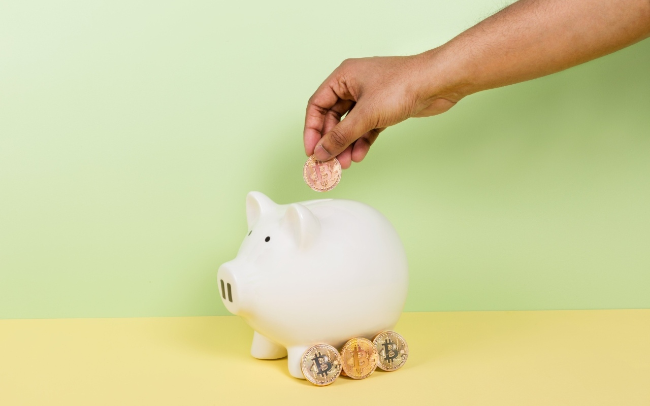 Рука бросает монету в свинью копилку