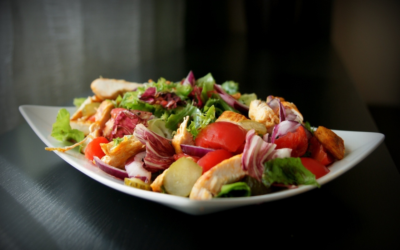 Аппетитный салат в белой тарелке на черном фоне