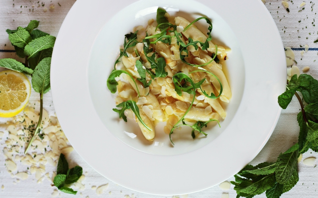 Блюдо с листьями рукколы в большой белой тарелке