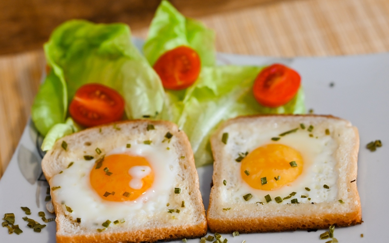 Яичница с хлебом, помидорами и листьями салата на завтрак