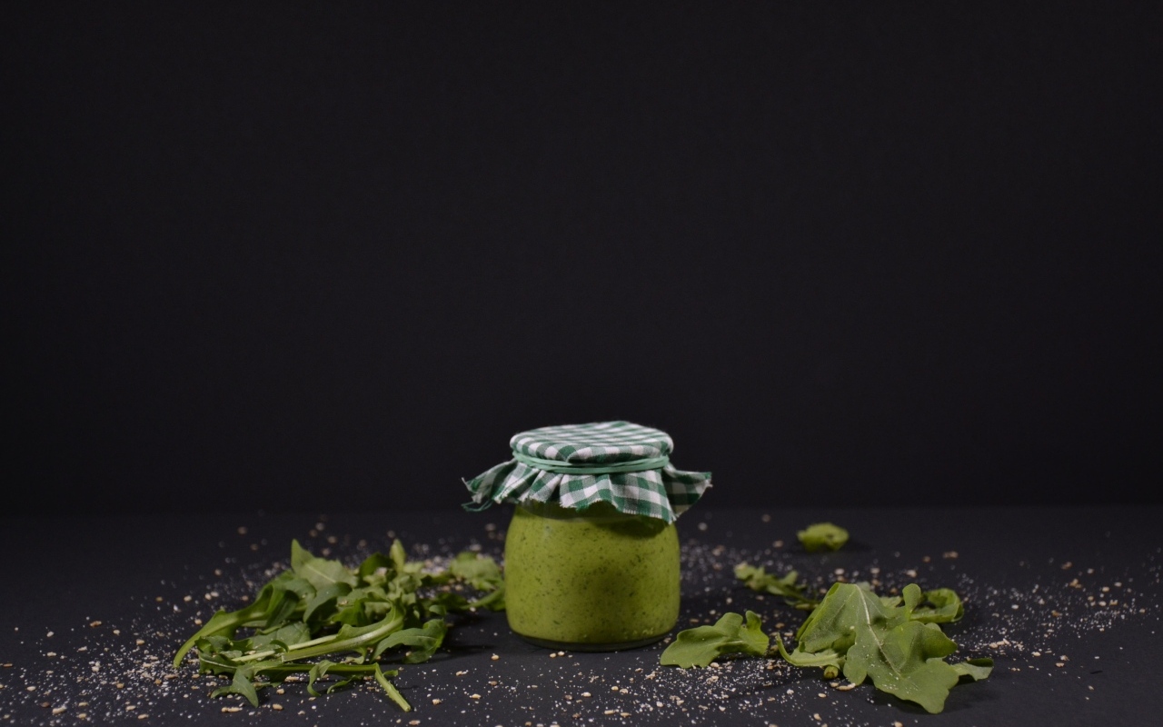 Банка соуса песто на черном фоне