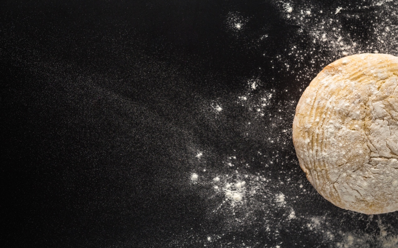 Сырое тесто на черном столе с мукой