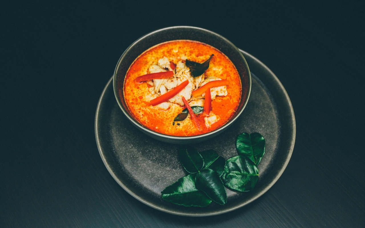 Острый суп в тарелке на черном фоне