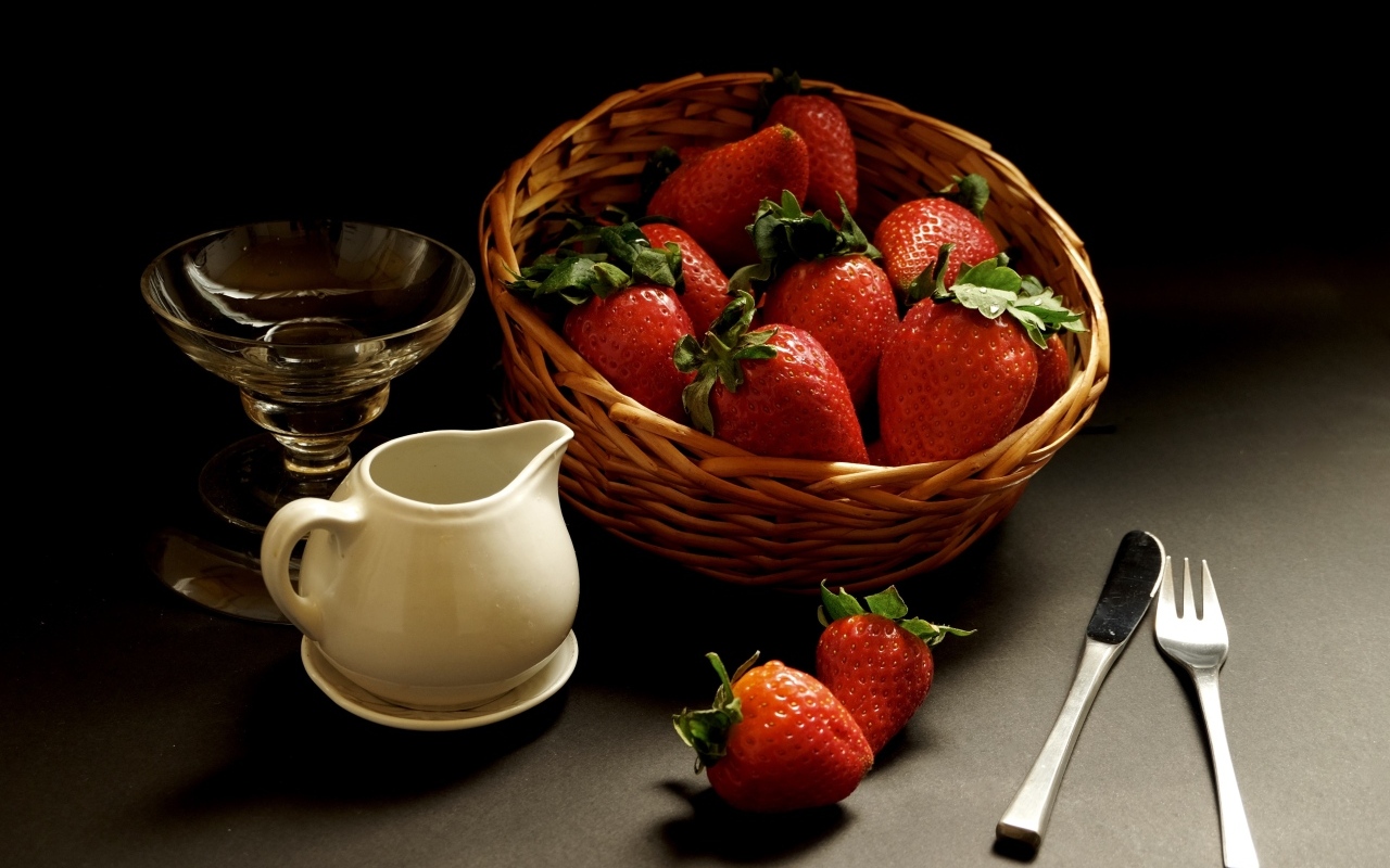 Корзина со спелой красной клубникой на столе с посудой