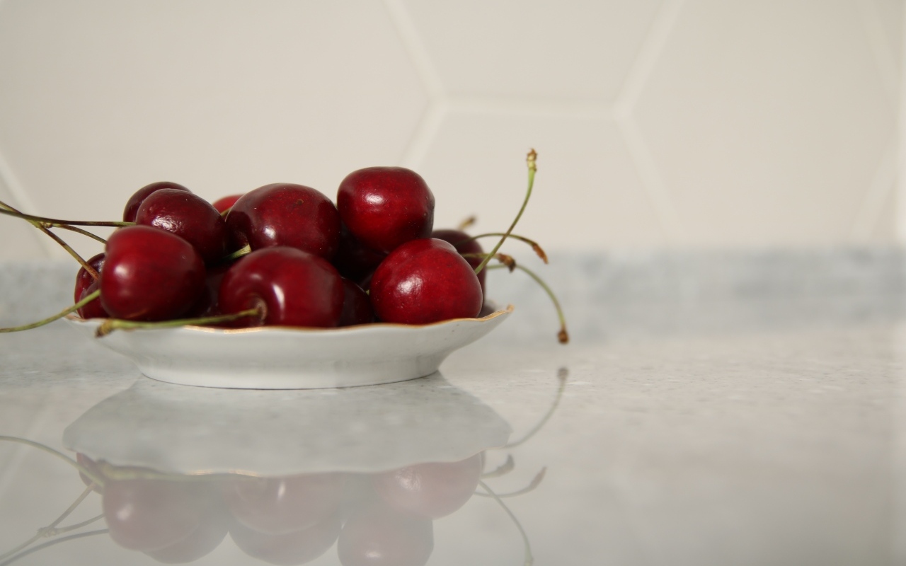 Вкусные сладкие черешни на белой тарелке
