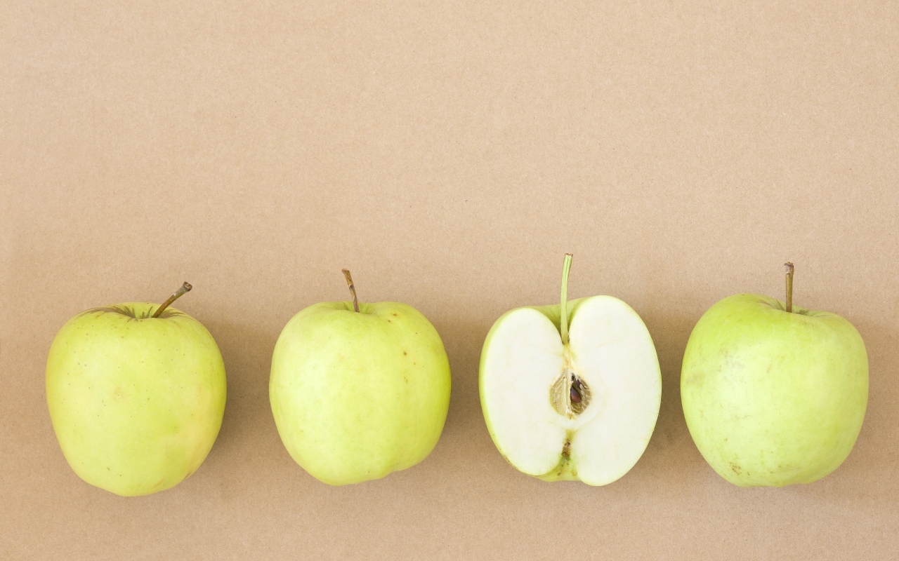 Четыре зеленых яблока на бежевом фоне 