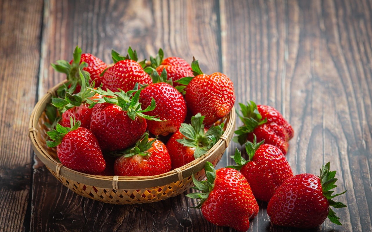 Много спелой красной клубники в деревянной посуде 