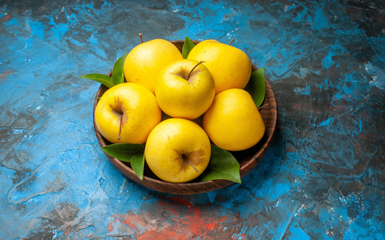 Деревянная тарелка с яблоками на столе