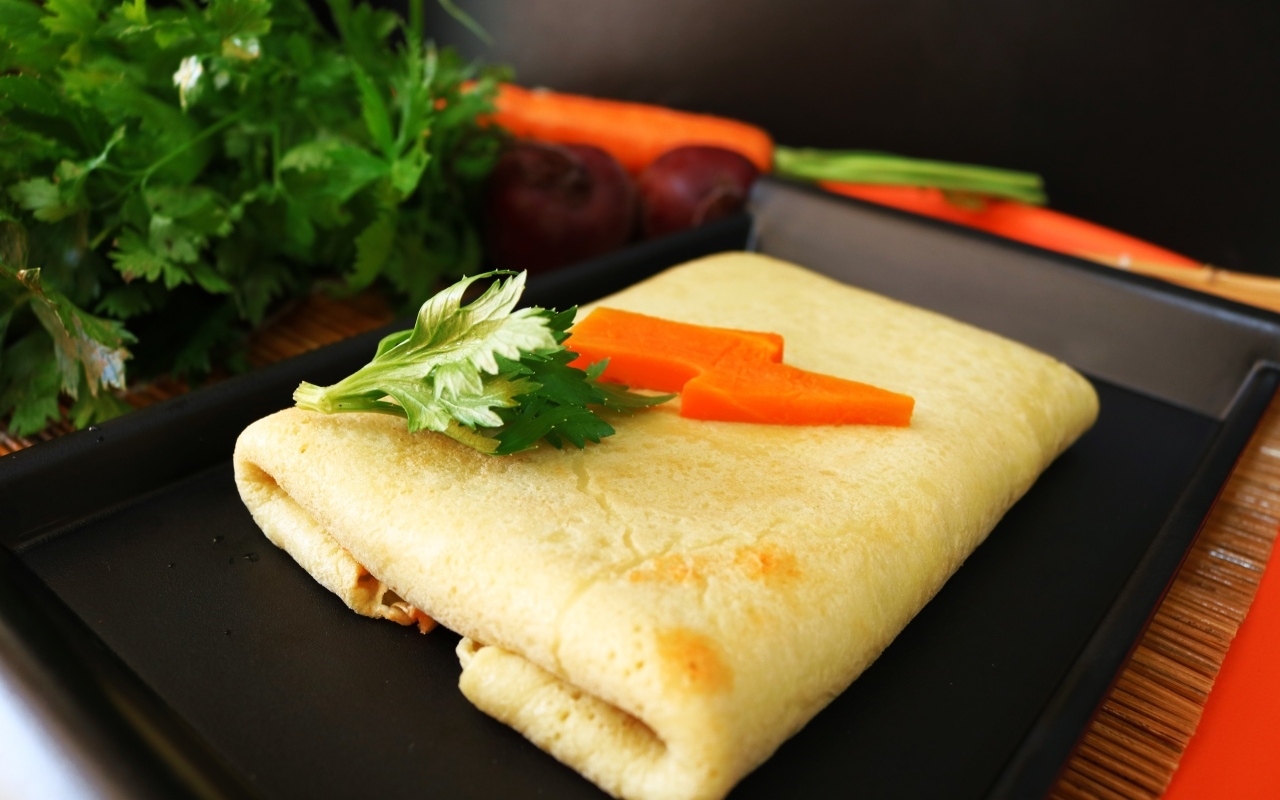 Блинчик на тарелке с морковью и веточками петрушки