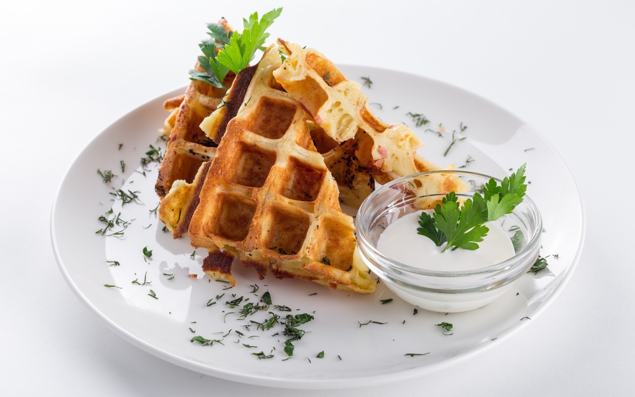 Вафли с соусом и зеленью на тарелке