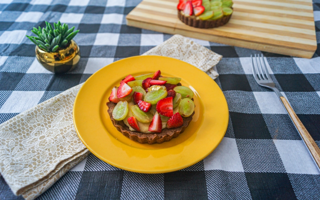 Пирожное с кремом и ягодами клубники и винограда