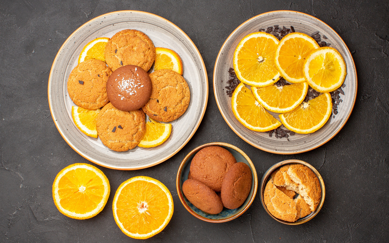 Вкусное печенье на тарелке с апельсинами