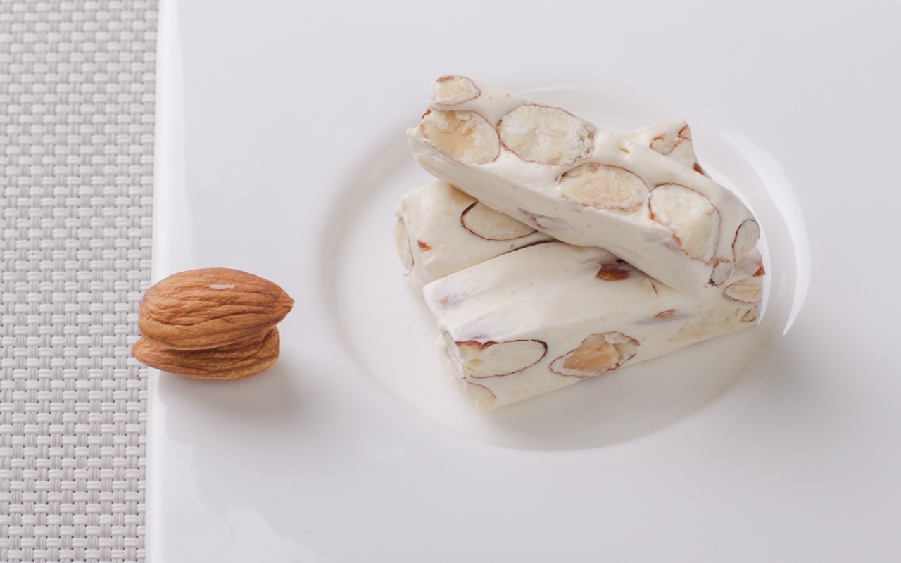 Десерт нуга с миндальными орехами на тарелке 