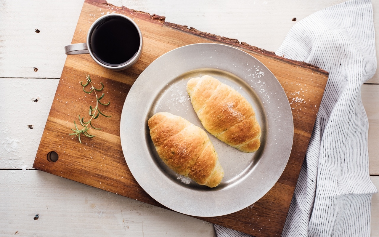 Два круассана на тарелке с чашкой кофе