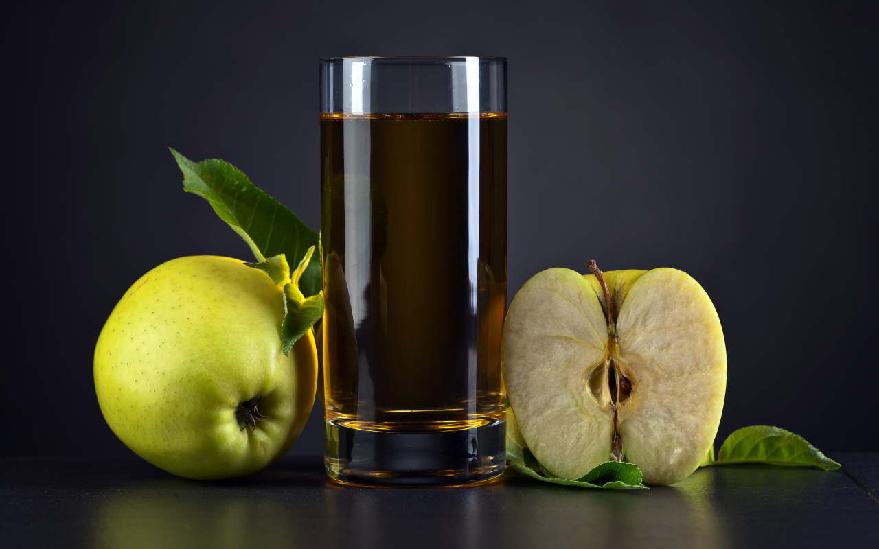 Стакан сока с зелеными яблоками на сером столе