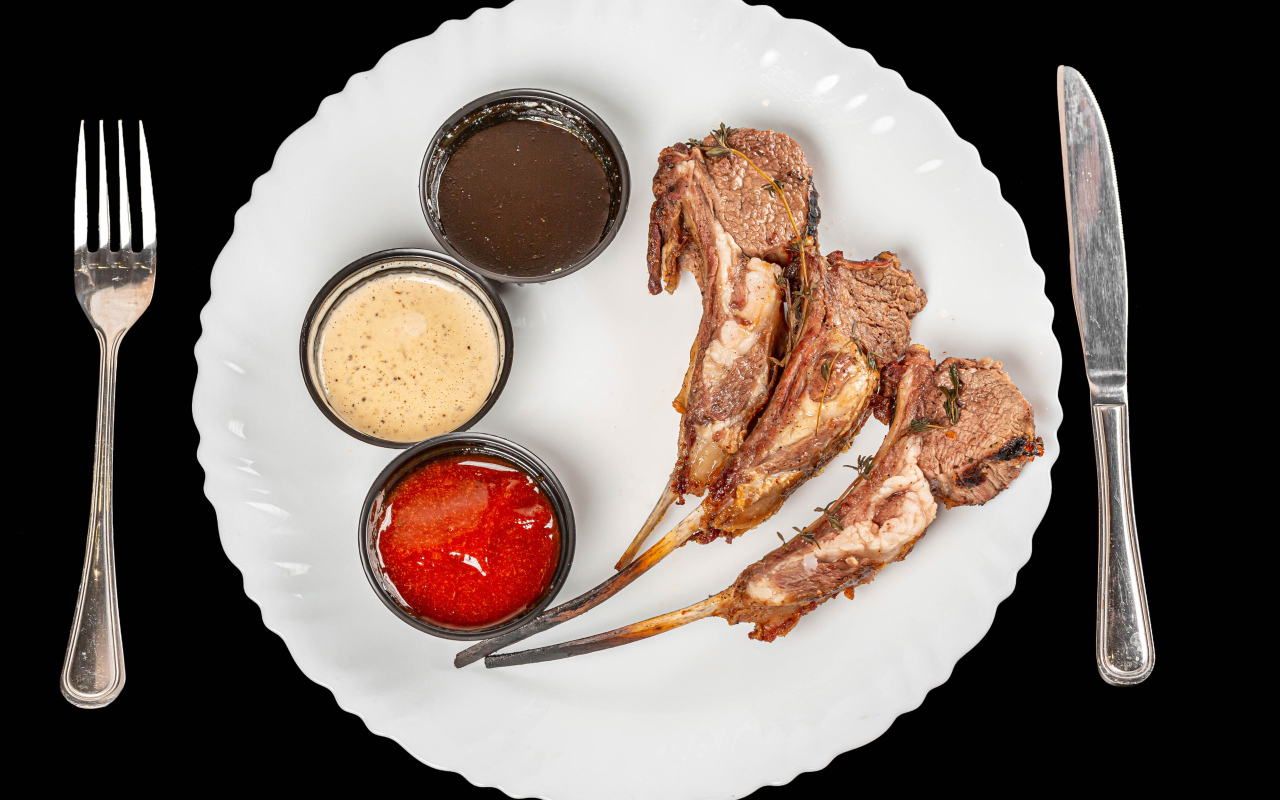 Свиные ребра с соусом на белой тарелке 