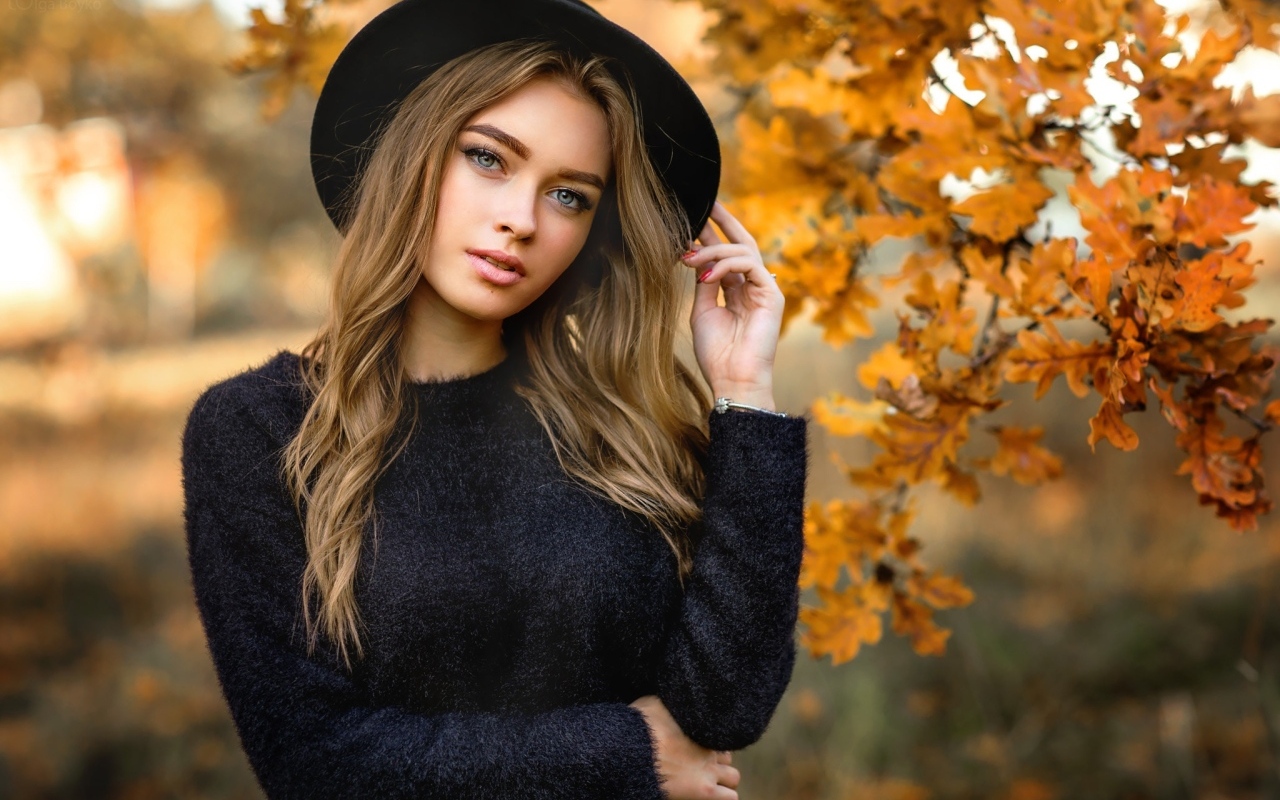 Девушка в черной шляпе стоит у дуба