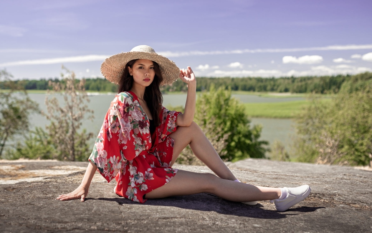 Девушка азиатка в шляпе лежит на камне