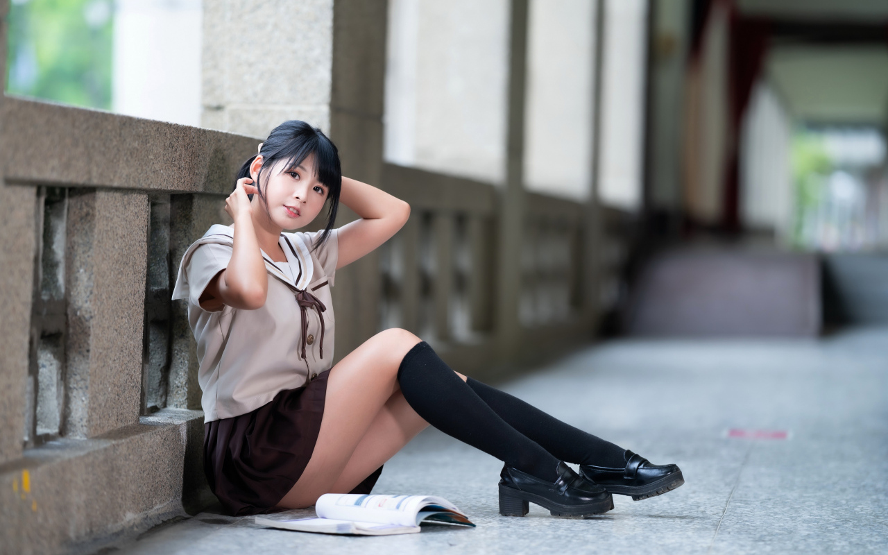 Девушка азиатка в школьной форме сидит на полу