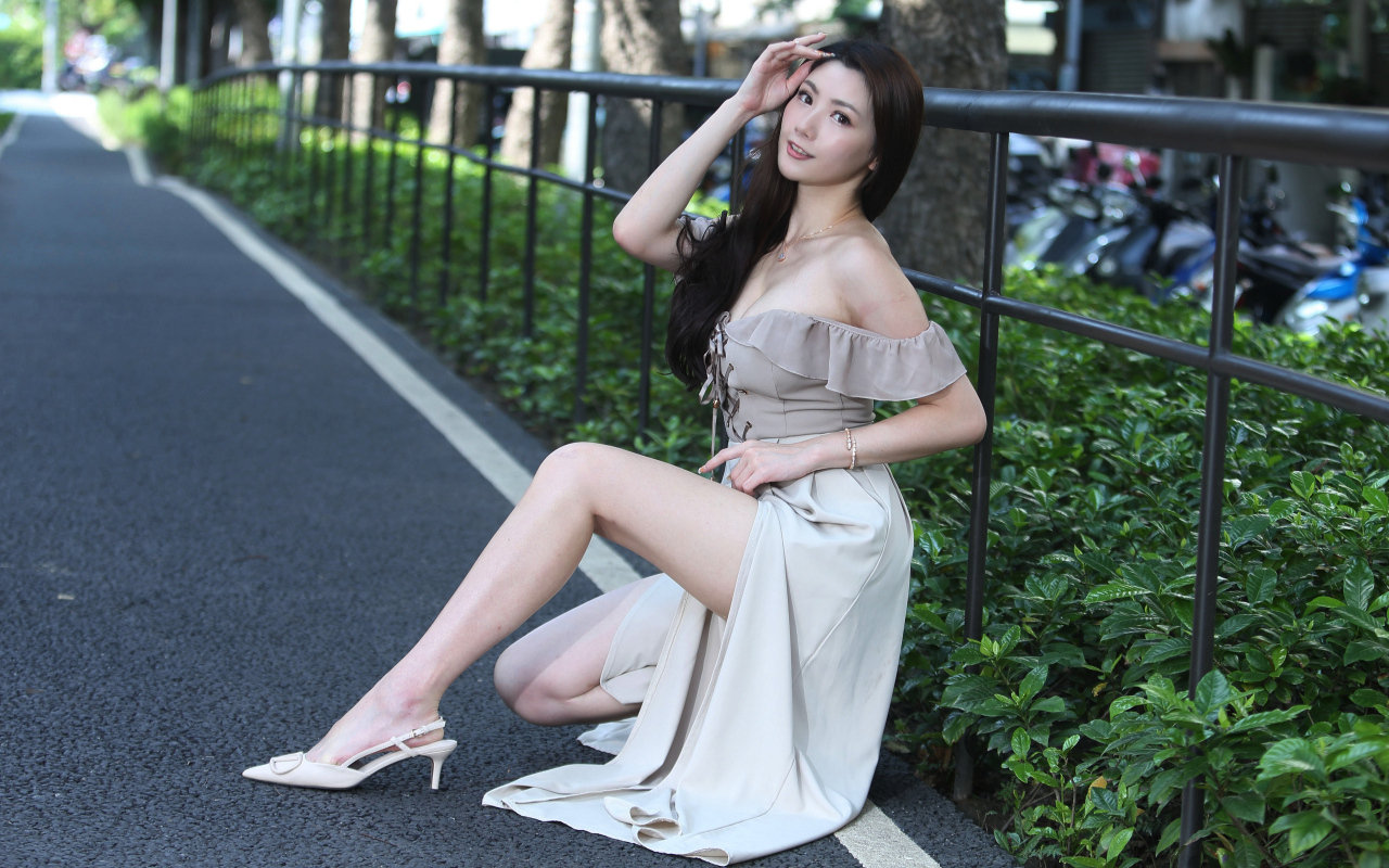 Девушка азиатка сидит у забора