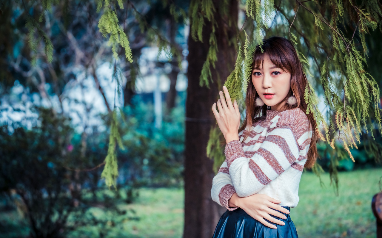 Девушка азиатка стоит у дерева ели