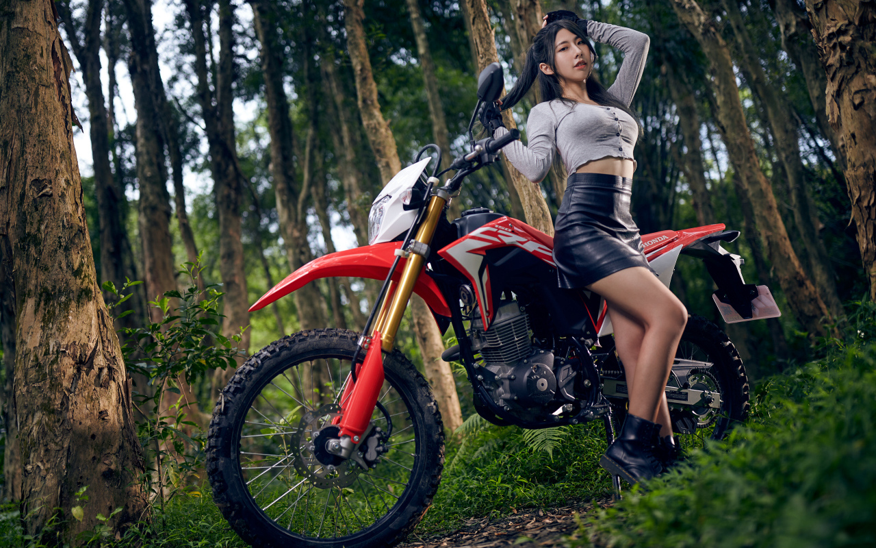 Девушка азиатка с мотоциклом в лесу
