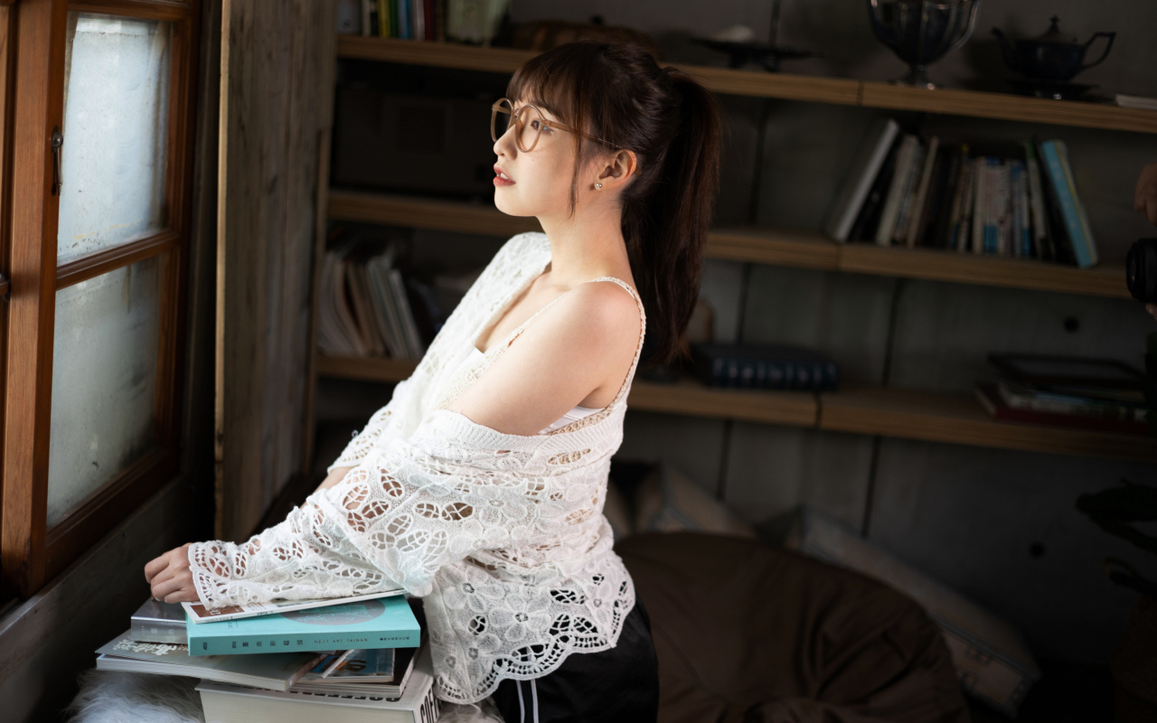 Девушка азиатка с книгами у окна