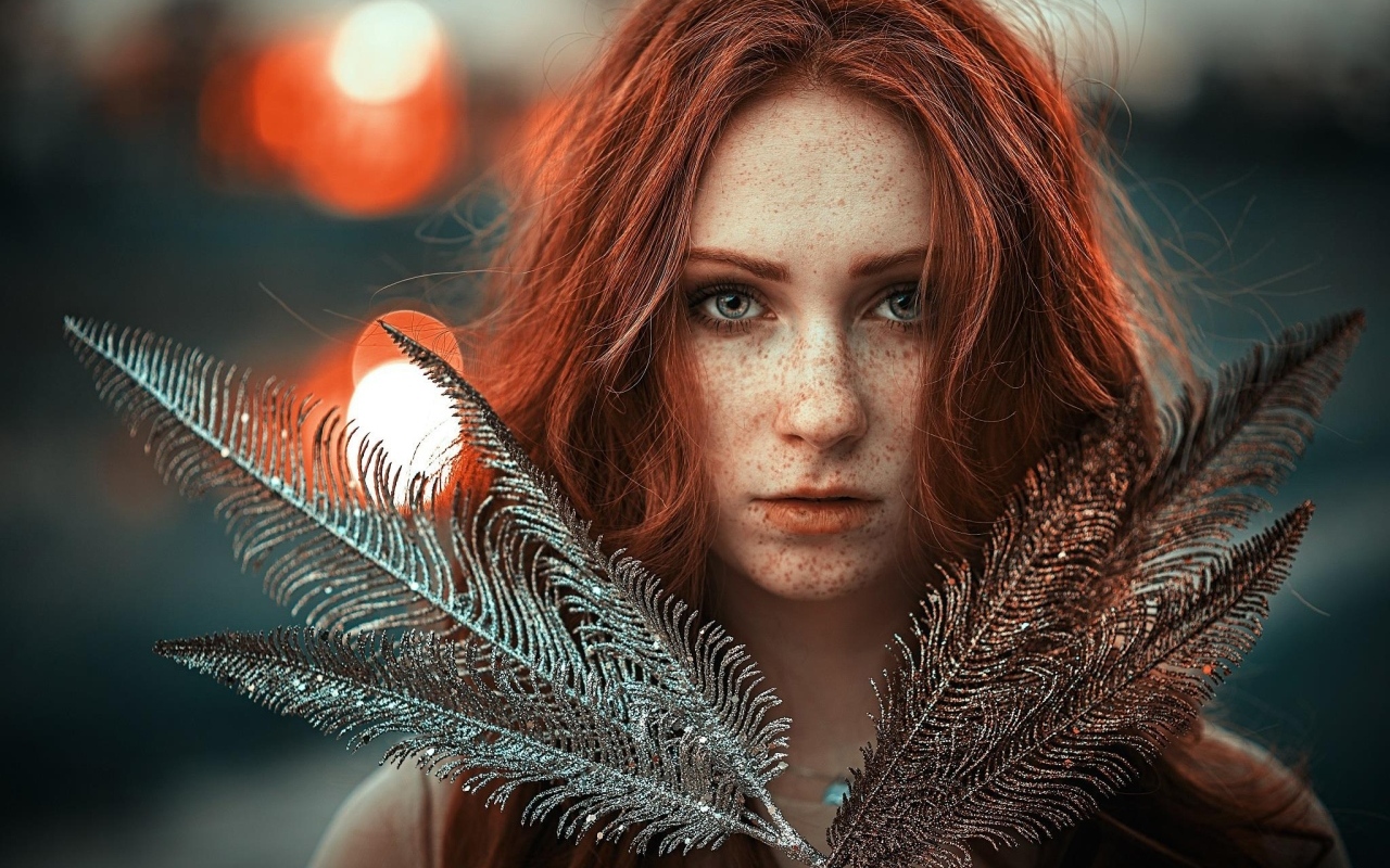 Яркая рыжеволосая девушка с перьями в руках