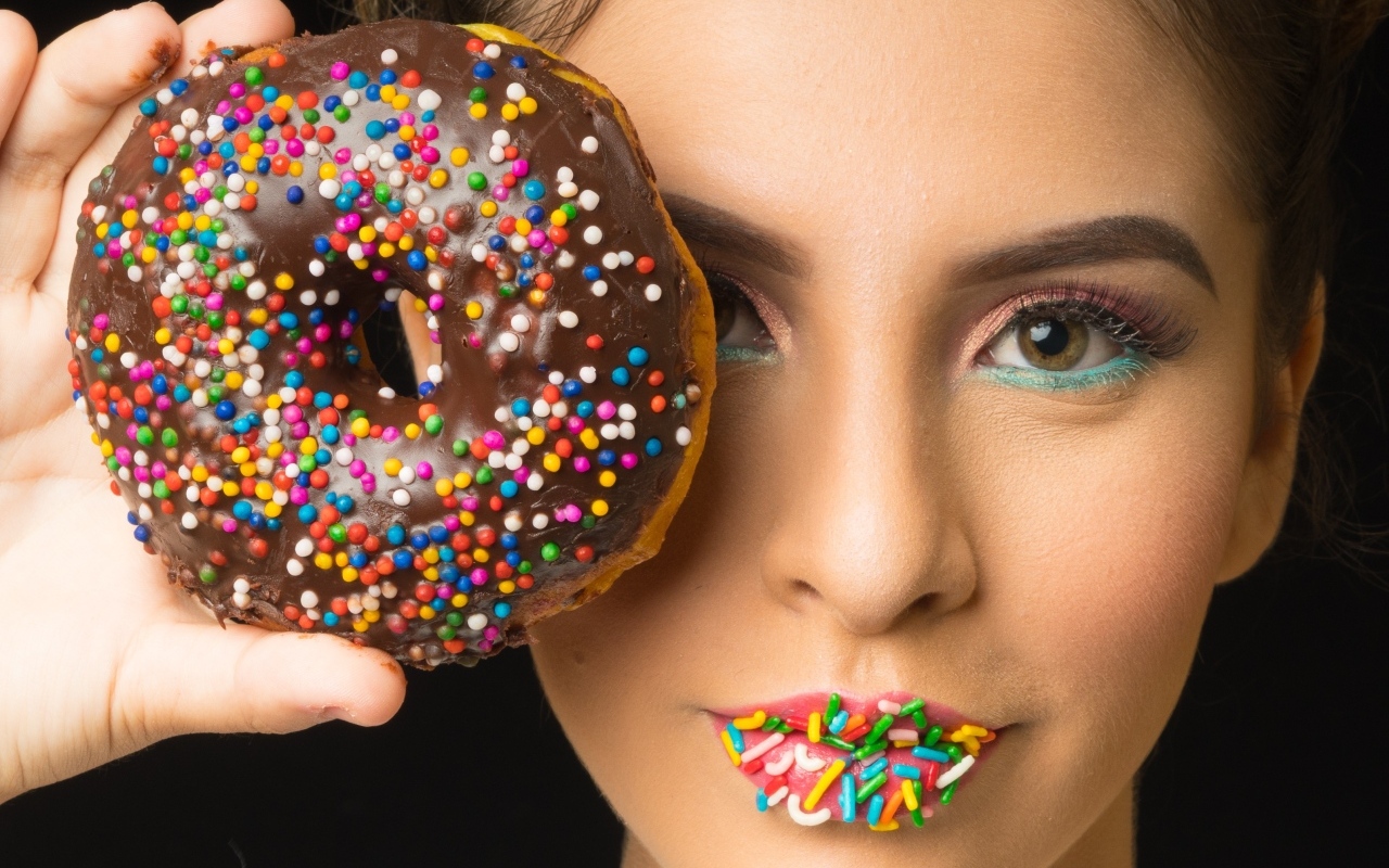 Девушка с пончиком в шоколаде в руках