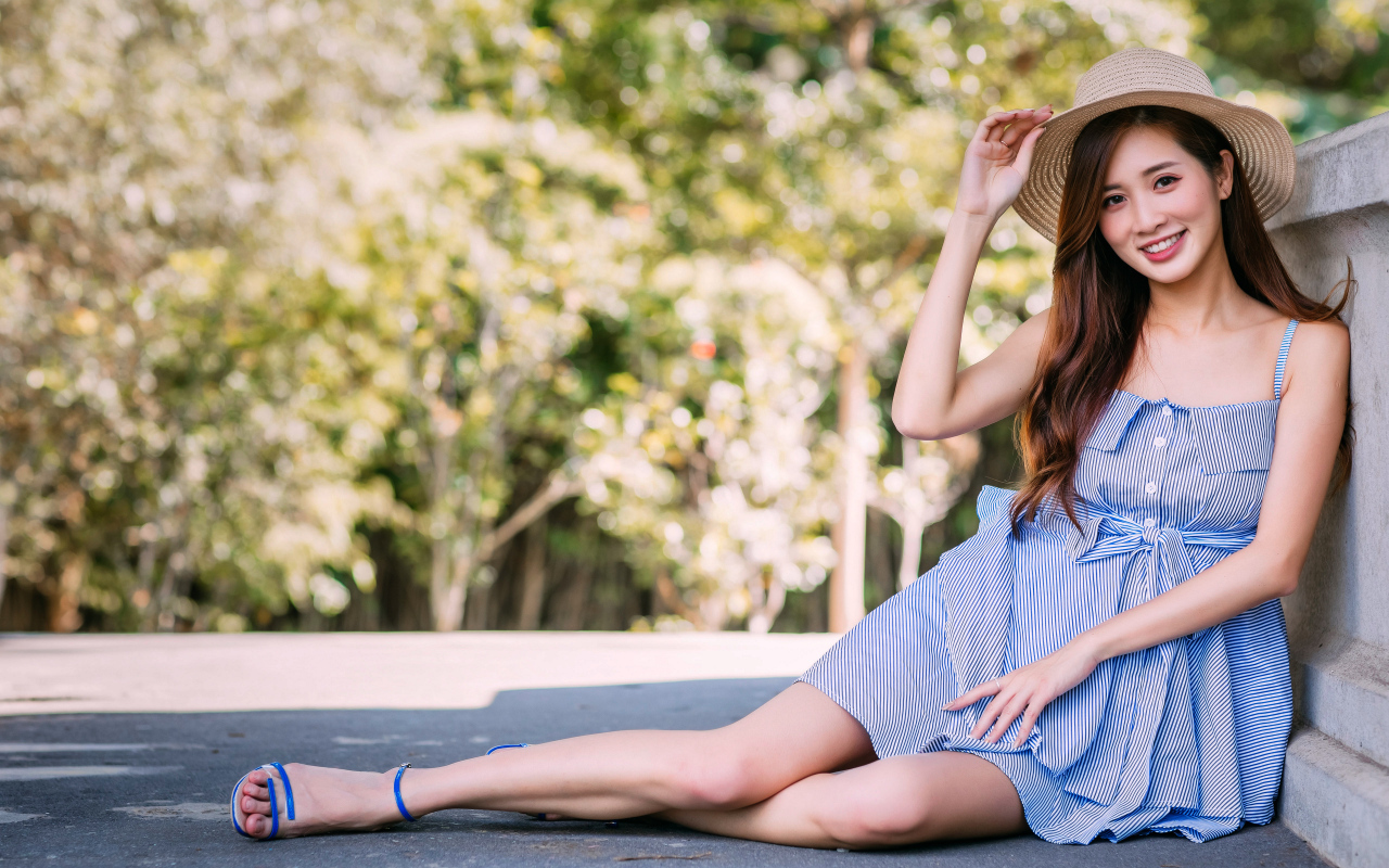 Улыбающаяся девушка азиатка сидит на асфальте